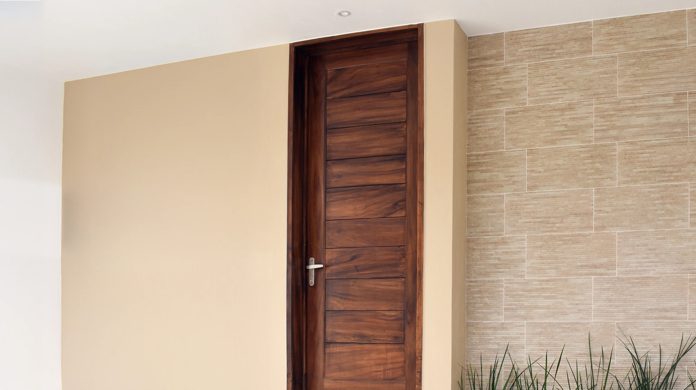 Un artisan en t-shirt bleu installe une serrure sur une porte d'entrée blanche dans un intérieur résidentiel