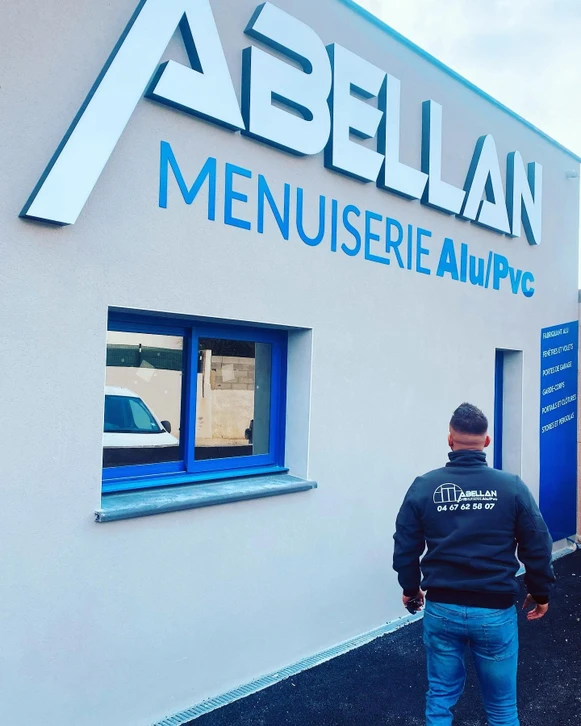 Atelier de menuiserie avec deux artisans souriants consultant un ordinateur portable sur établi